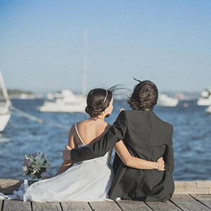 Young couple sitting on a jetty and looking at the river