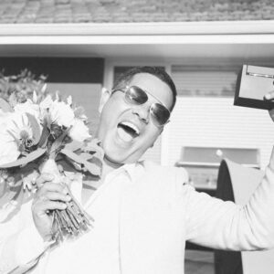 best man with sunglasses celebrating a wedding with a flower bouquet in his hand and the ring in the other one