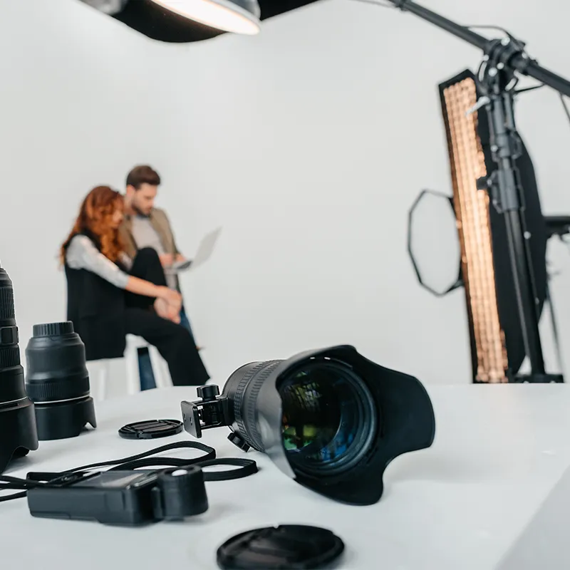 Professional photographer prepares to digitise large artwork in a white studio surround with strobes and camera lenses in the foreground