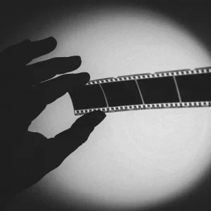 the silhouette of a hand holding a negative strip against the light