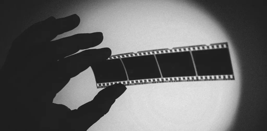close up of the silhouette of a hand holding a negative strip against the light