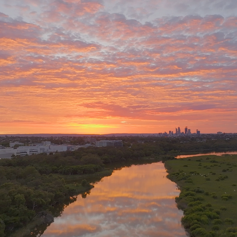 Aerial view of Perth city during sunrise with epic clouds at the back and reflection on the lake